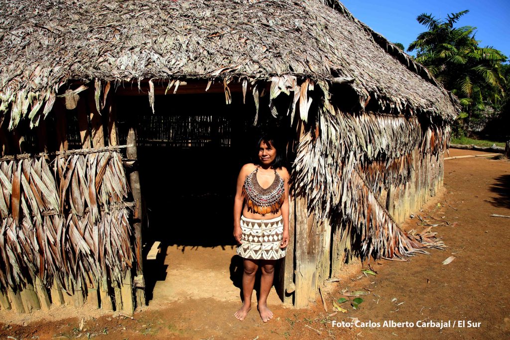 Nativa Bora junto a una Maloca (casa ceremonial) en la selva amazónica peruana. Foto: Carlos Alberto Carbajal