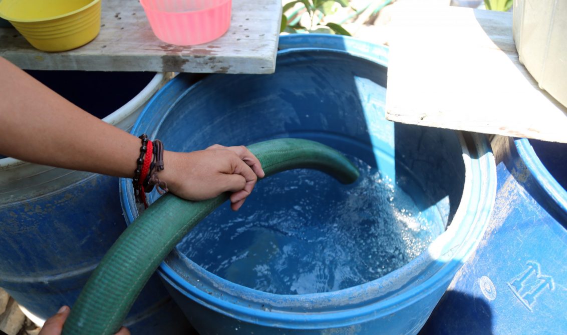 Un vecino del barrio de San Antonio quien no cuenta con el servicio de agua potable desde hace mas de un mes, llena sus tinas y tambos de una pipa de agua potable, la cual comprarán en 300 pesos por 4 mil litros. Foto: Jesús Eduardo Guerrero