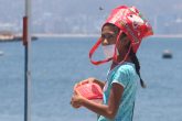 Acapulco,Gro/25Mayo2020/ Una niña se cubre la cabeza con una bolsa ante el intenso calor del medio día de ayer, mientras hace fila para recibir un porción de alimentos en la cocina comunitaria instalada en el Malecón de Acapulco. Foto: Jesús Trigo