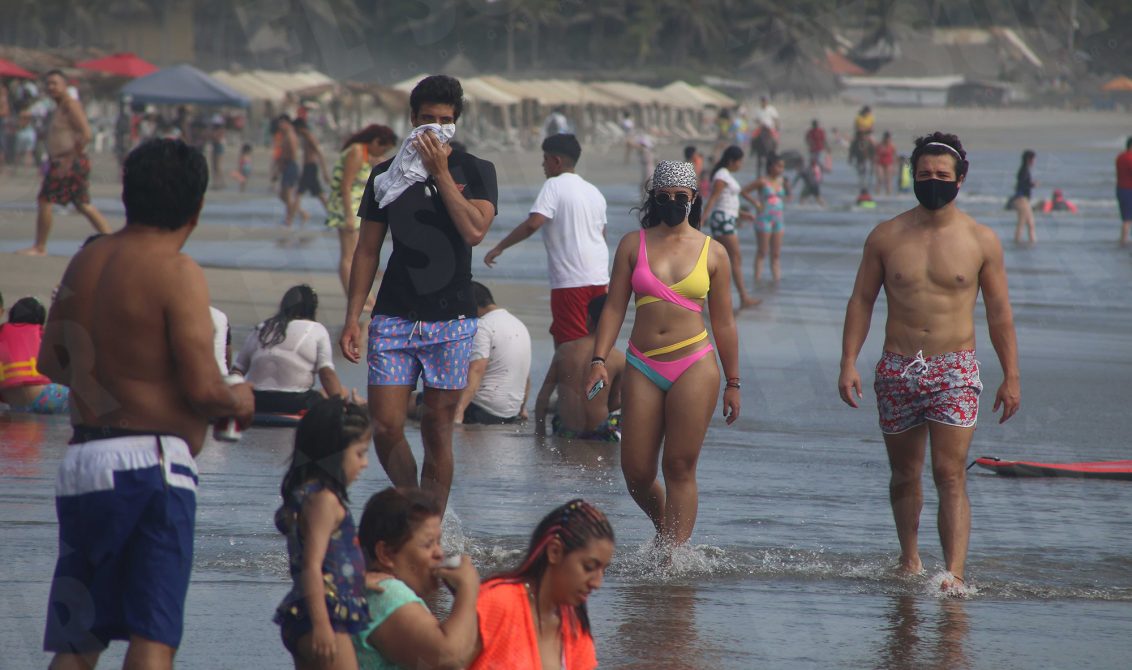 25 de Diciembre del 2020 Acapulco, Guerrero. Turistas utilizan cubre bocas y uno mas improvisa con una playera para cubrirse nariz y boca, mientras toman una caminata entre los cientos de bañistas que ayer visitaron la playa Revolcadero. Foto: Carlos Alberto Carbajal