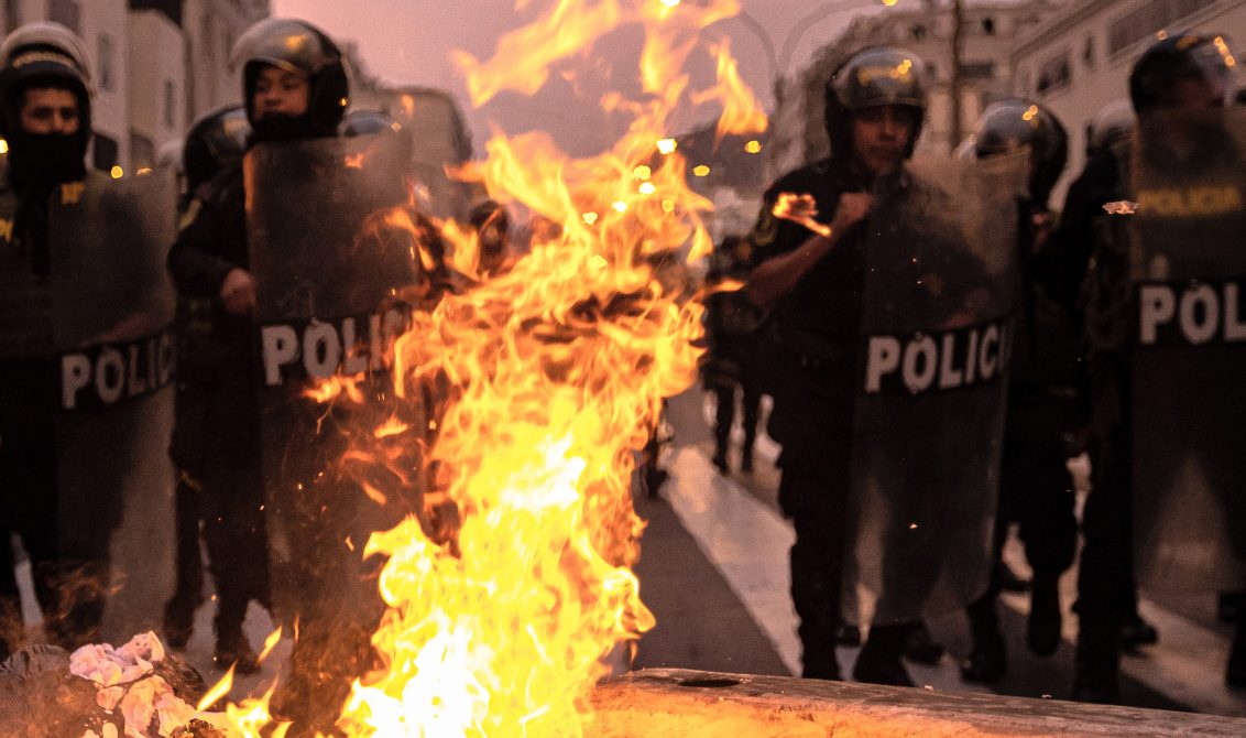 08 December 2022, Peru, Lima: Police officers stand behind burning barricades ignited by supporters of Peru's ousted President Castillo during a demonstration following Peru's Congress vote on Wednesday to remove Castillo from office and replace him with the vice president, shortly after Castillo tried to dissolve the legislature ahead of a planned vote on his ouster. Photo: Lucas Aguayo Araos/dpa